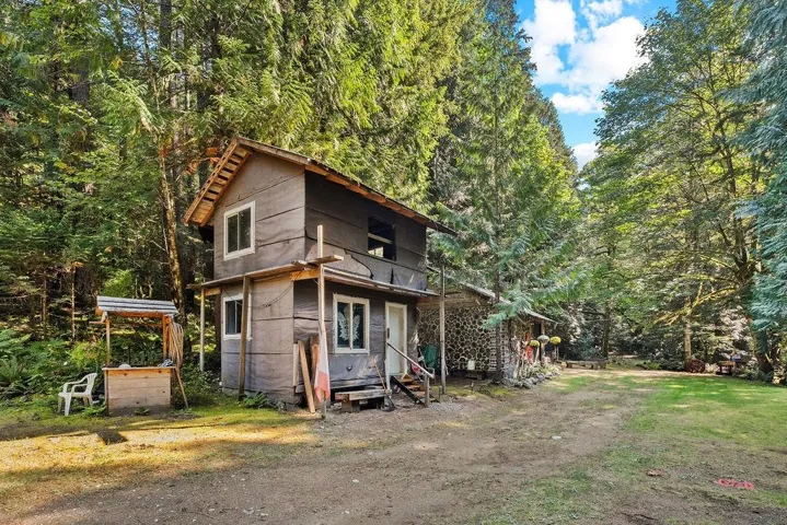 View of front of home with a balcony and a forest view
