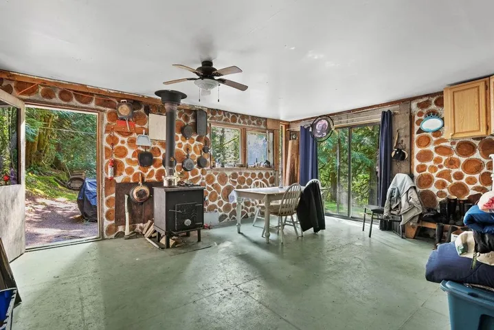 Sitting room with a wood stove, concrete flooring, healthy amount of natural light, and ceiling fan