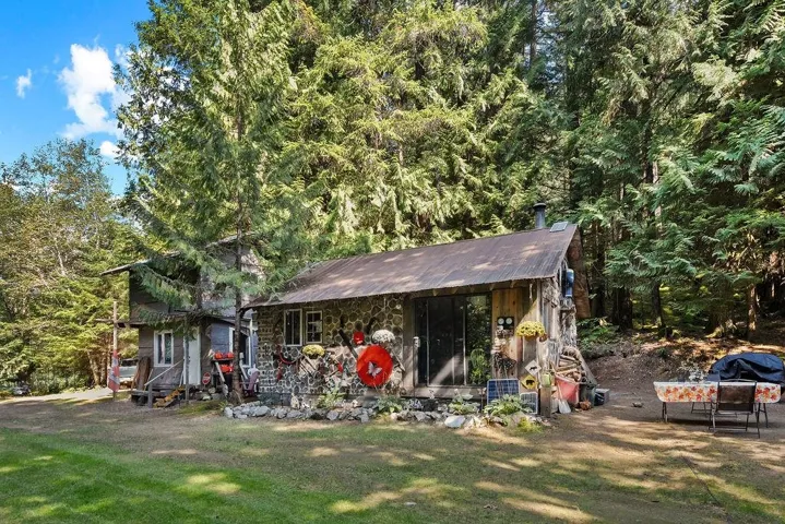 View of front facade featuring a front yard, a forest view, and stone siding