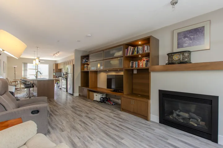 Living area featuring light wood-style flooring and a glass covered fireplace