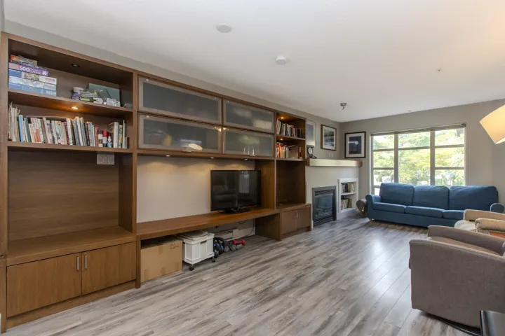 Living area with light wood-style floors, a glass covered fireplace, and built in desk
