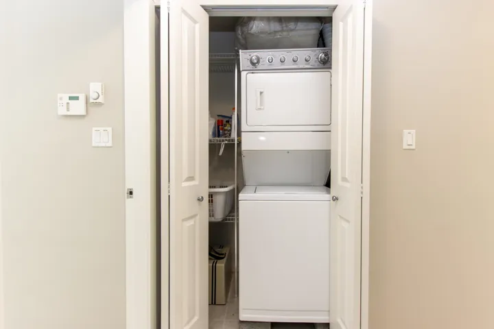 Laundry area featuring estacked washer and dryer and light tile patterned floors