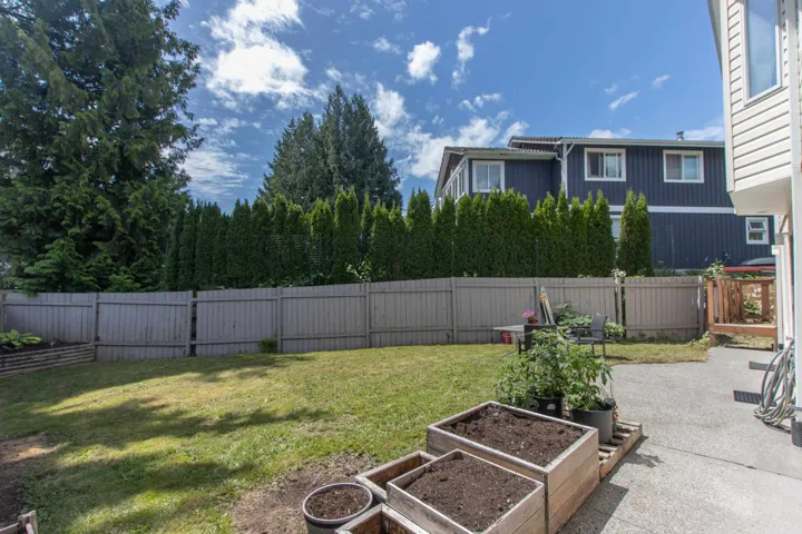 Fenced backyard with a vegetable garden and a patio