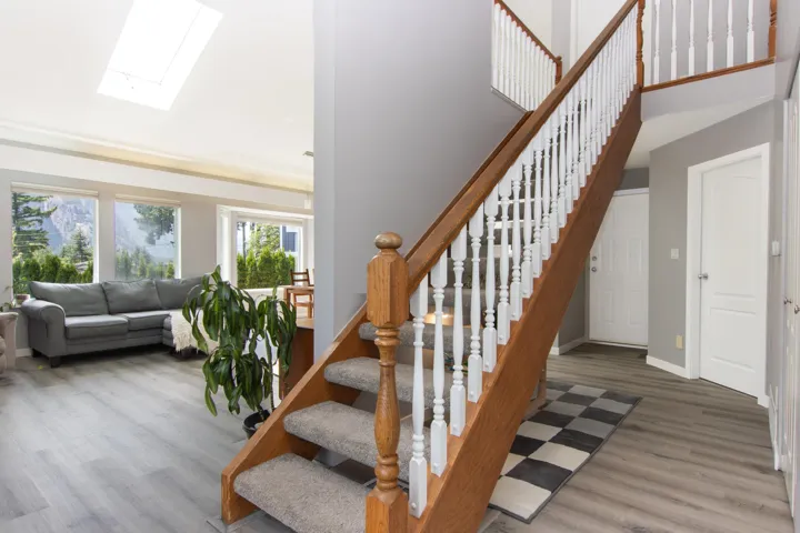 Stairway featuring a skylight, wood finished floors, and a high ceiling