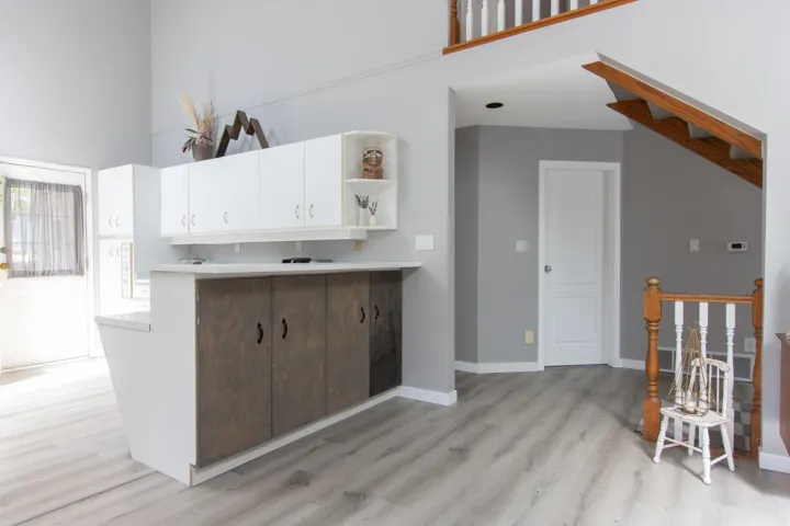 Kitchen with open shelves, light wood-style floors, white cabinets, a high ceiling, and light countertops