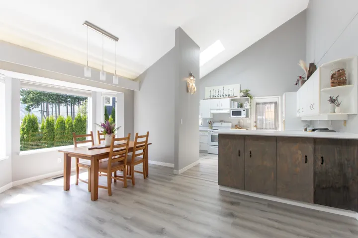 Dining space with light wood-style flooring, high vaulted ceiling, and a skylight