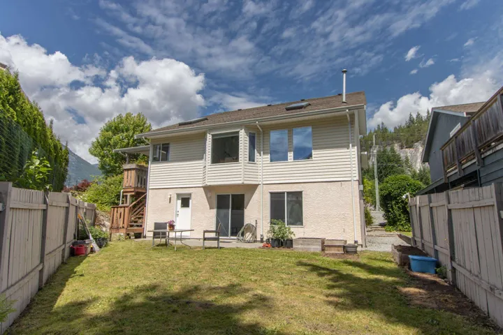 Back of property featuring a fenced backyard, stairs, and stucco siding