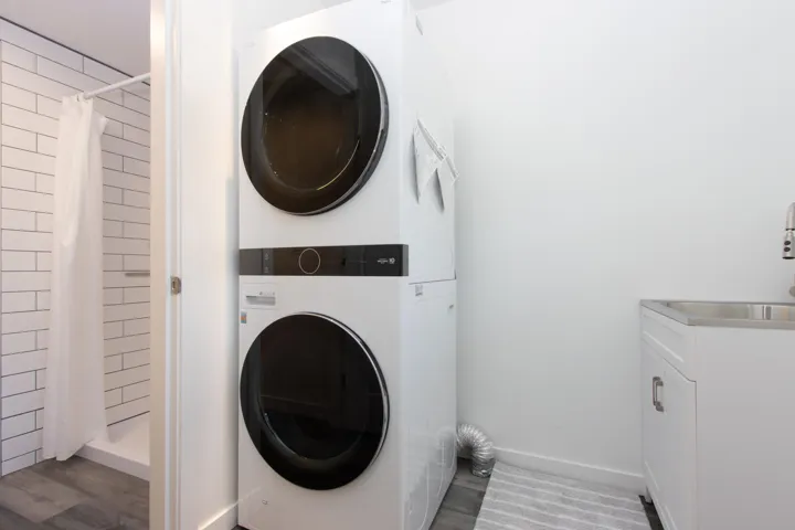 Laundry room with stacked washing machine and dryer, cabinet space, and wood finished floors