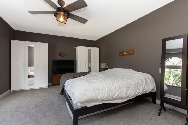 Bedroom featuring carpet floors, vaulted ceiling, and a ceiling fan