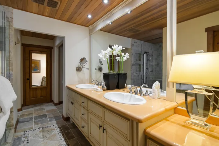 Full bath featuring visible vents, tiled shower, wood ceiling, and a sink