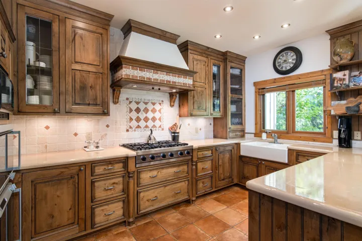 Kitchen featuring light countertops, a sink, stainless steel gas stovetop, custom range hood, and decorative backsplash