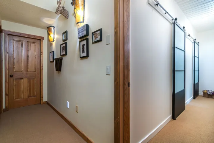 Hall with baseboards, a barn door, and light carpet
