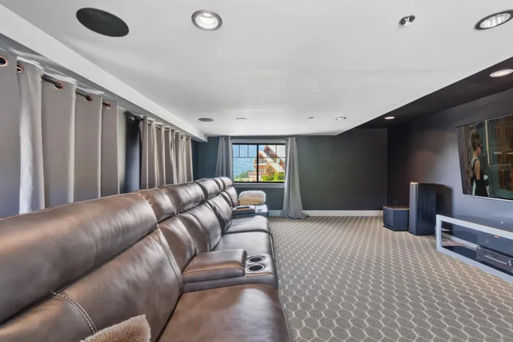 Spacious room featuring patterned carpeting, recessed lighting, a window with exterior visibility, and a ceiling-mounted speaker