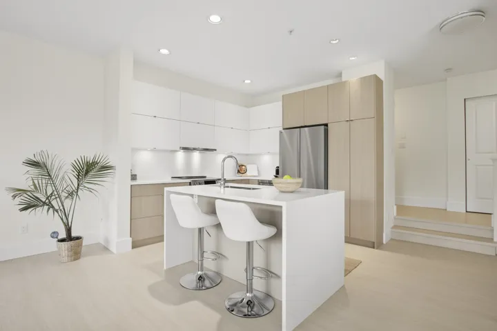 Contemporary kitchen featuring a large center island, integrated stainless steel appliances, light wood-finish flooring, recessed lighting, and white flat-panel cabinetry