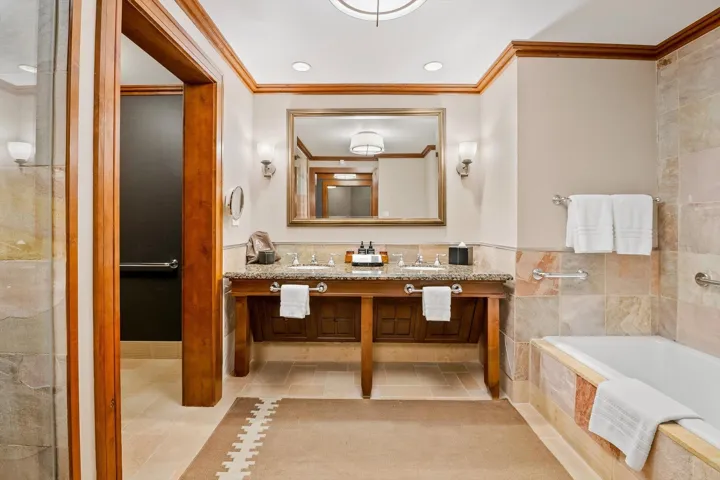 Bathroom featuring tile walls, vanity, crown molding, and tiled tub