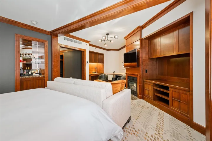 Bedroom with ornamental molding, a glass covered fireplace, and suspended lighting