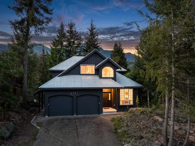 Dark-toned exterior siding with a light-colored metal roof, arched window detailing, and an attached two-car garage