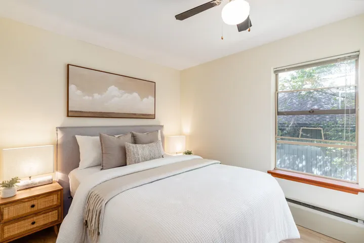 Bright bedroom featuring neutral wall tones and wood-finish flooring