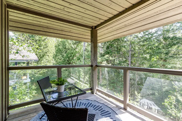 Outdoor balcony featuring wood-finish decking, a clear glass railing, and a slatted wood-finish ceiling
