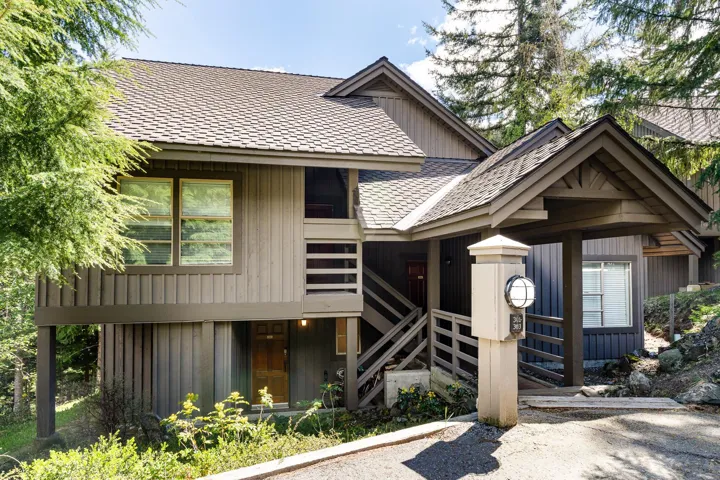 Multi-level property featuring vertical wood siding, a gabled roofline, and an integrated covered entryway