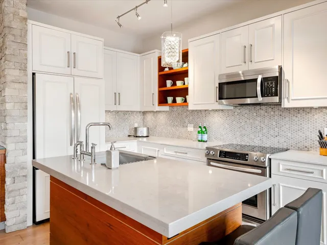 Kitchen with open shelves, decorative backsplash, a sink, white cabinets, and appliances with stainless steel finishes