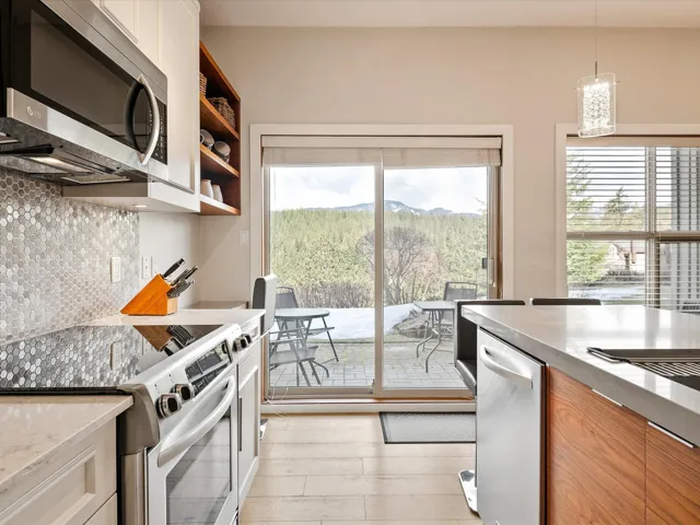 Kitchen featuring tasteful backsplash, hanging light fixtures, a mountain view, a notable chandelier, and appliances with stainless steel finishes