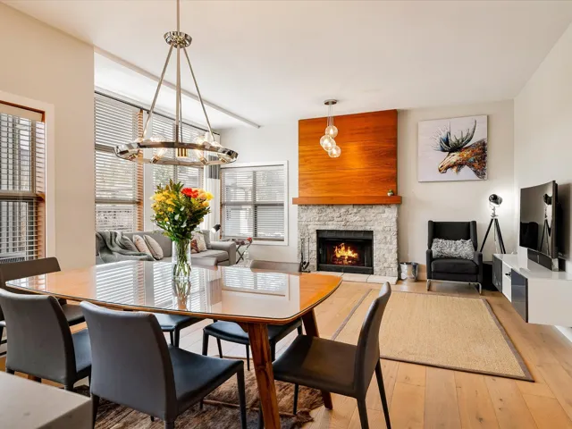 Dining room with a stone fireplace, a notable chandelier, and light wood-style flooring