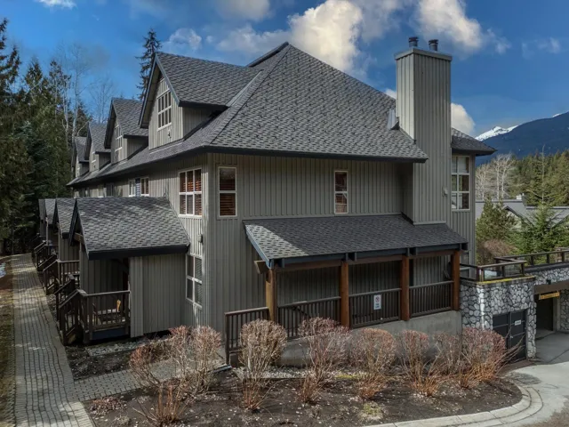 Back of property featuring a chimney, concrete driveway, a porch, a garage, and a shingled roof