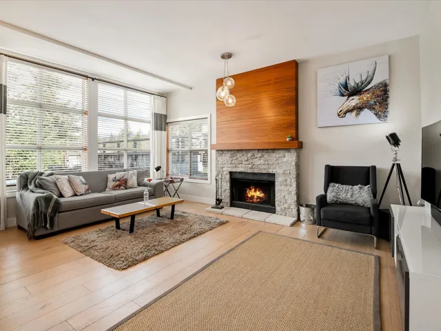Living area with a stone fireplace, baseboards, a healthy amount of sunlight, and light wood finished floors