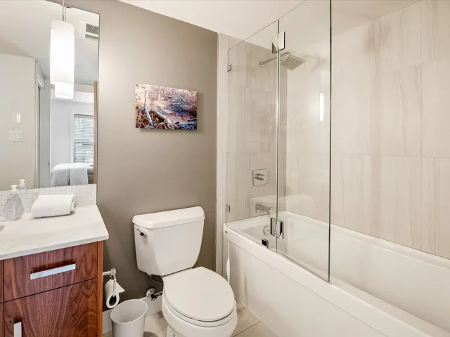Full bathroom featuring visible vents, toilet, bath / shower combo with glass door, and vanity