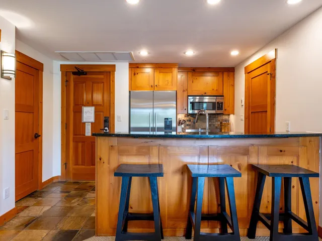 Kitchen featuring stainless steel appliances, brown cabinets, a breakfast bar, decorative backsplash, and dark stone countertops