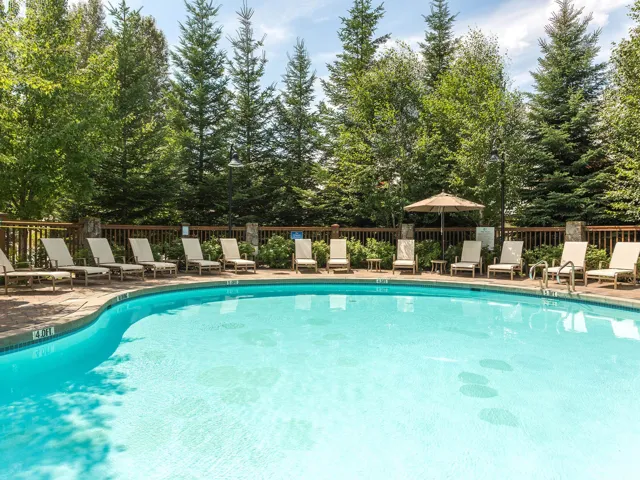 Community pool with a patio and view of scattered trees