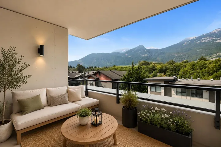 Outdoor balcony featuring a glass railing, wall-mounted light fixture, and a mountain backdrop
