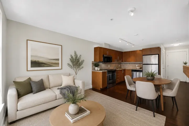 Open concept living area with wood-finish flooring, recessed lighting, and a kitchen featuring stainless steel appliances and wood cabinetry