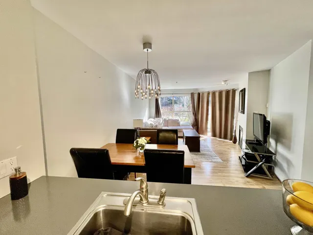 Open-concept living area featuring a modern chandelier, light wood-finish flooring, and a built-in fireplace