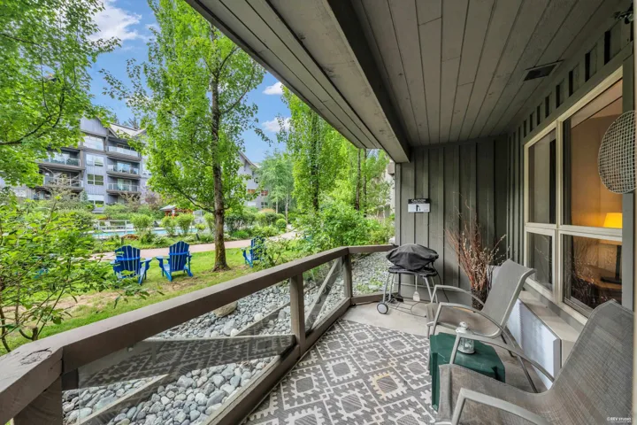 Private balcony featuring a geometric pattern outdoor rug, glass railing, and wood-finish siding