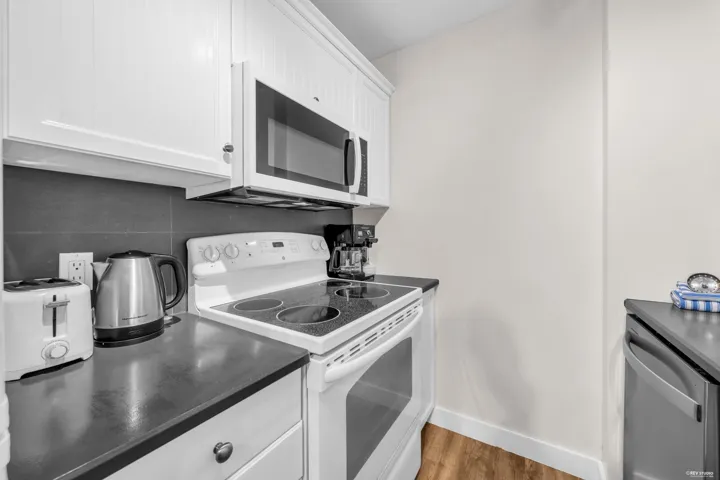 Kitchen featuring white cabinetry, dark countertops, a tile backsplash, and wood-finish flooring