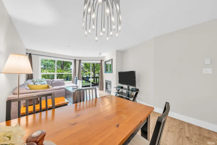Dining area with a wood-finish table and modern chandelier, featuring wood-finish flooring