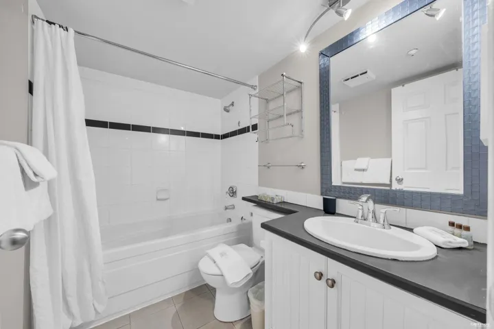 Bathroom featuring a tub/shower combination with white subway tile surround and black accent stripe