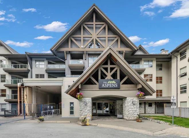 Multi-story condominium building featuring a prominent gabled entrance with decorative wood-finish beams