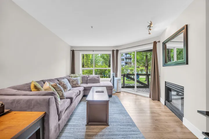 Living room with wood-finish flooring, a modern linear fireplace, and a large sliding glass door opening to an outdoor patio space