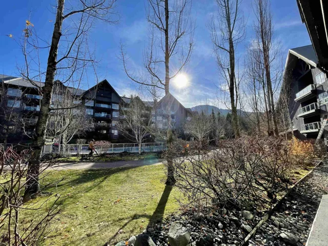 Landscaped grounds featuring a green lawn area, mature deciduous trees, and shrubbery