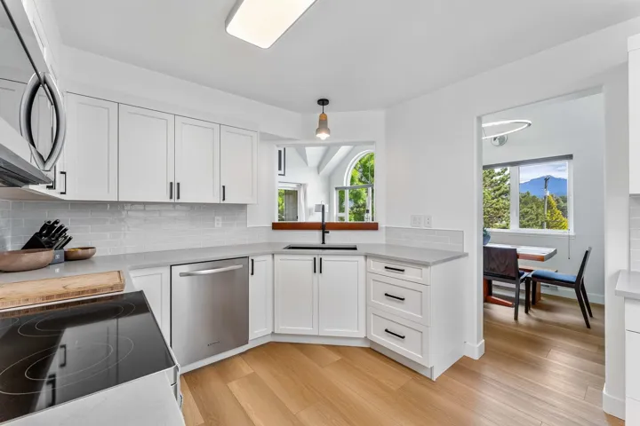 Kitchen with white cabinets, decorative backsplash, stainless steel appliances, and light wood-type flooring