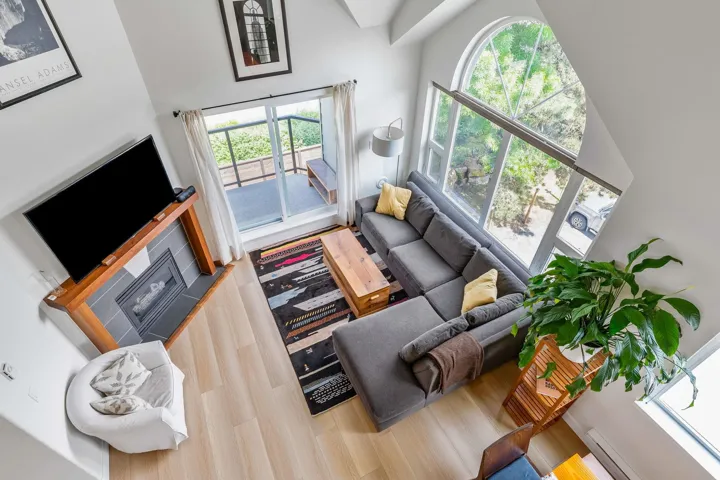 Living room with a high ceiling, a baseboard heating unit, and light wood-style floors