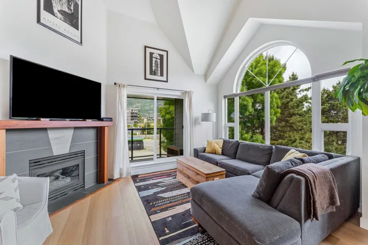 Living room with vaulted ceiling, light wood finished floors, and a fireplace