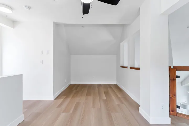 Empty room featuring lofted ceiling, light wood-type flooring, and a ceiling fan