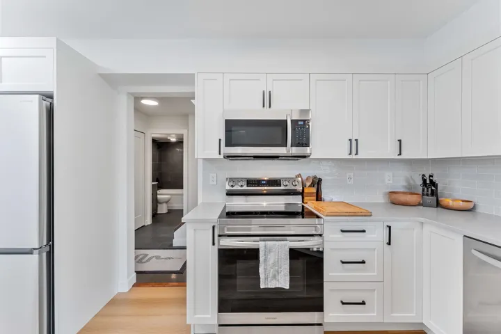 Kitchen featuring stainless steel appliances, white cabinets, and tasteful backsplash