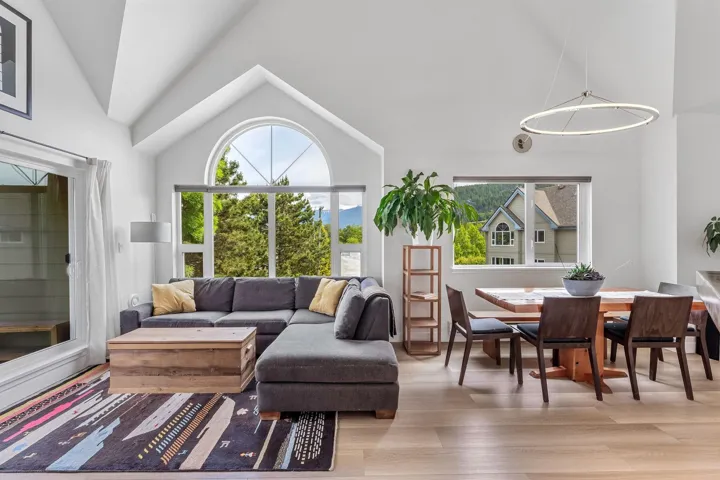 Living area featuring vaulted ceiling, light wood finished floors, healthy amount of natural light, and a chandelier