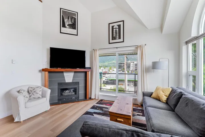 Living area featuring vaulted ceiling, wood finished floors, a fireplace, and plenty of natural light