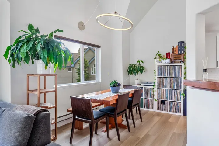 Dining space with light wood finished floors, lofted ceiling, and a baseboard heating unit